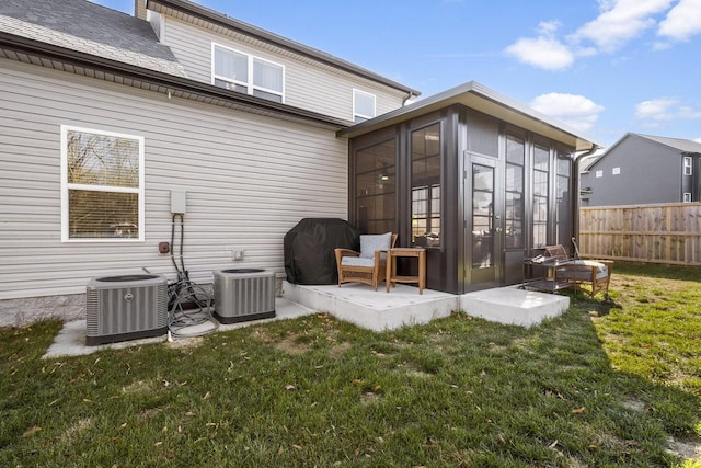 rear view of house with a lawn, a sunroom, and central air condition unit