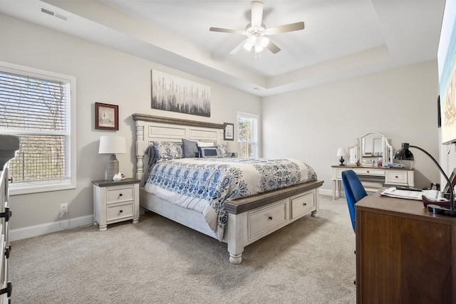 carpeted bedroom with ceiling fan and a raised ceiling