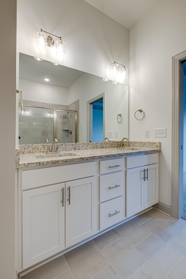 bathroom featuring a sink, double vanity, a shower stall, and tile patterned floors