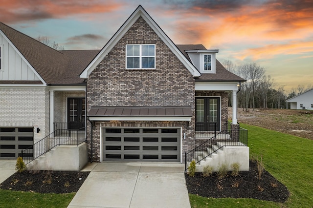 view of front of property with brick siding, a front lawn, french doors, driveway, and an attached garage