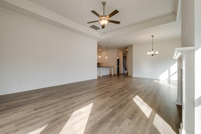 unfurnished living room featuring hardwood / wood-style flooring, ornamental molding, ceiling fan with notable chandelier, and a tray ceiling