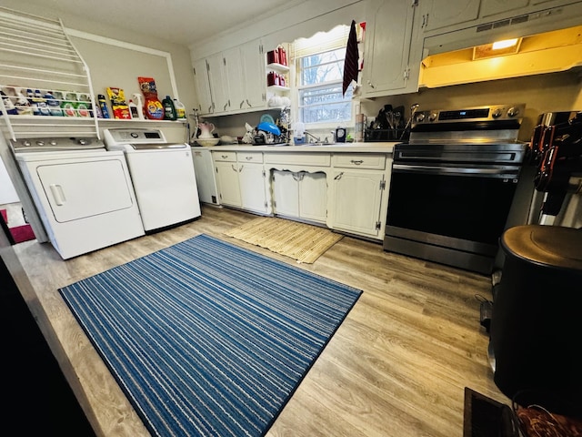 kitchen with stainless steel electric stove, washing machine and clothes dryer, and light hardwood / wood-style floors