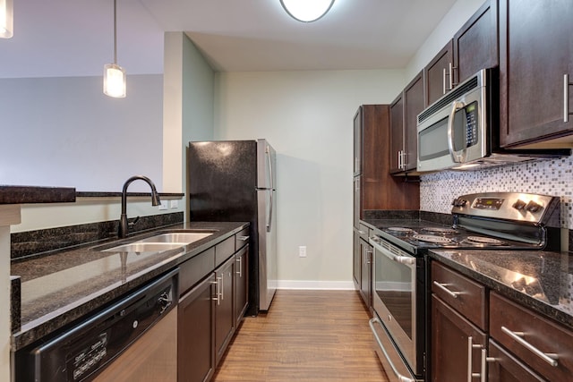 kitchen with sink, dark stone counters, hanging light fixtures, dark brown cabinetry, and stainless steel appliances