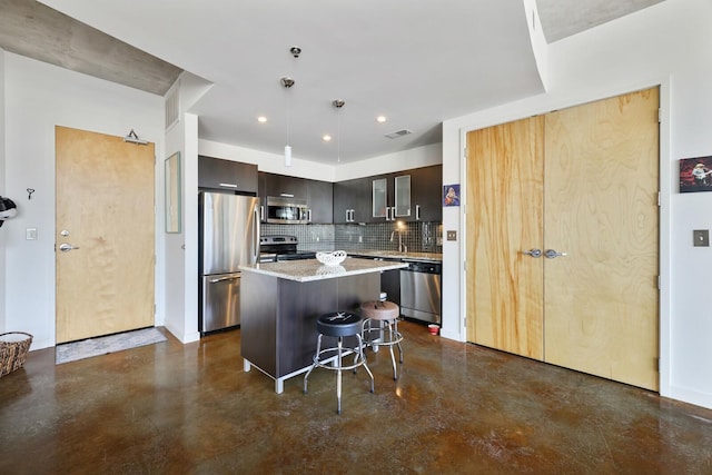 kitchen with visible vents, a kitchen breakfast bar, a center island, stainless steel appliances, and backsplash