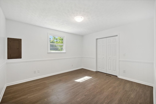 6992 Mill Creek Rd, Lyles, TN 37098 - unfurnished bedroom with a textured ceiling, a wainscoted wall, dark wood-type flooring, visible vents, and electric panel