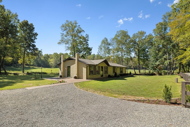 exterior space with driveway, a chimney, and a lawn