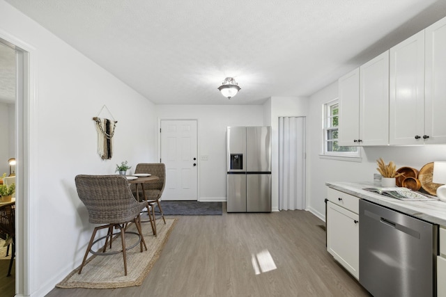 6992 Mill Creek Rd, Lyles, TN 37098 - kitchen featuring a textured ceiling, stainless steel appliances, baseboards, white cabinets, and light wood finished floors