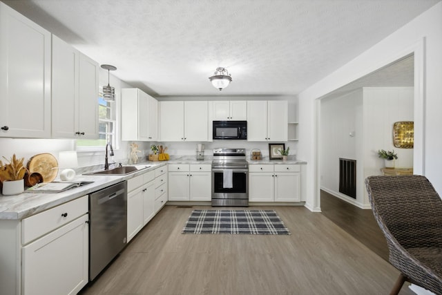 6992 Mill Creek Rd, Lyles, TN 37098 - kitchen with a sink, white cabinetry, hanging light fixtures, appliances with stainless steel finishes, and light countertops