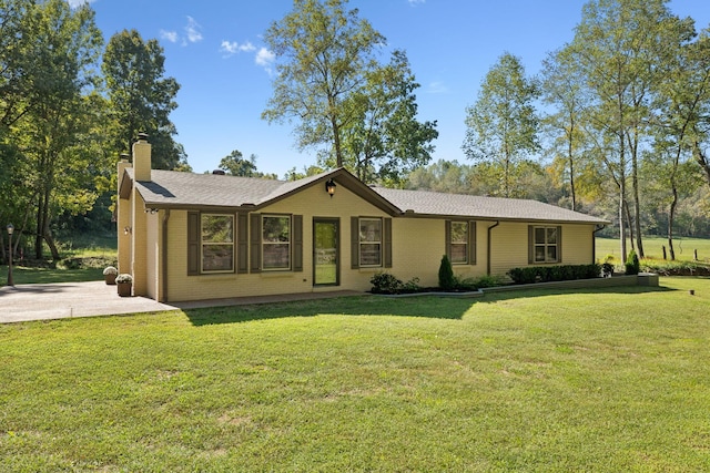 ranch-style house featuring brick siding, a chimney, concrete driveway, and a front yard