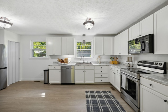 6992 Mill Creek Rd, Lyles, TN 37098 - kitchen with white cabinets, stainless steel appliances, light countertops, pendant lighting, and a sink
