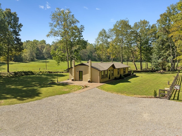 exterior space with gravel driveway, a chimney, and a front lawn