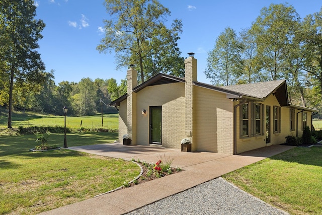 6992 Mill Creek Rd, Lyles, TN 37098 - view of home's exterior with a patio area, brick siding, a lawn, and a chimney