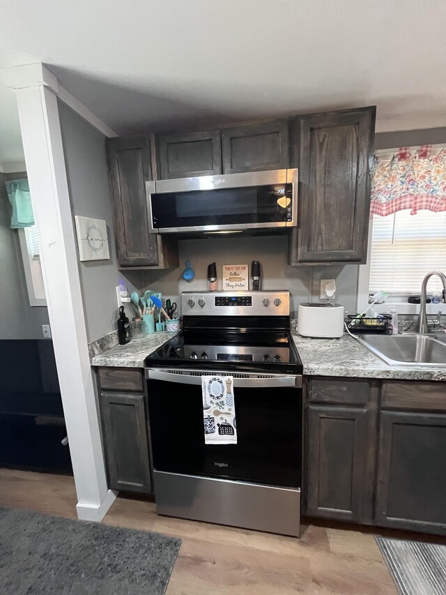 6992 Mill Creek Rd, Lyles, TN 37098 - kitchen featuring appliances with stainless steel finishes, a sink, dark brown cabinetry, and light wood-style floors