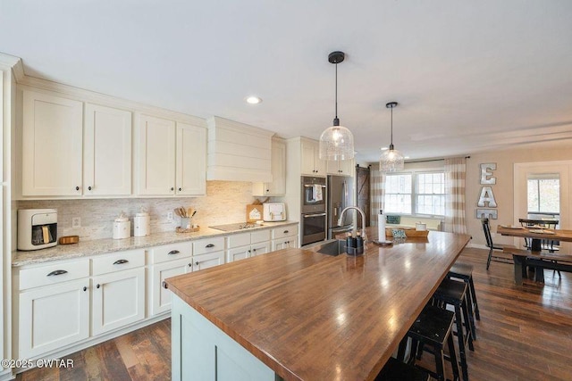 kitchen featuring hanging light fixtures, an island with sink, appliances with stainless steel finishes, and sink