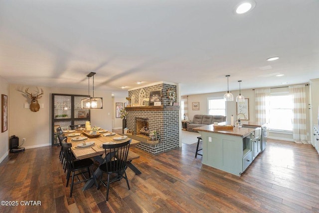 dining room featuring a brick fireplace, sink, and dark hardwood / wood-style flooring