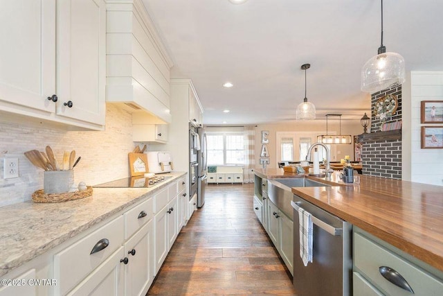 kitchen with butcher block counters, black electric cooktop, stainless steel dishwasher, pendant lighting, and white cabinets