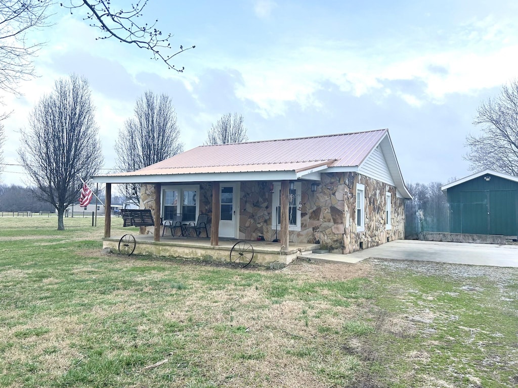 view of front of house featuring a storage unit, covered porch, a patio area, and a front yard