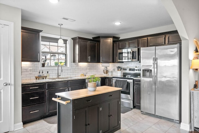 kitchen featuring sink, a kitchen island, decorative light fixtures, stainless steel appliances, and decorative backsplash