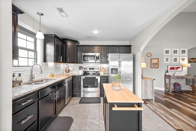 kitchen with sink, a center island, pendant lighting, stainless steel appliances, and tasteful backsplash