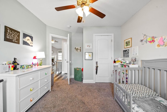 carpeted bedroom with ceiling fan and a crib