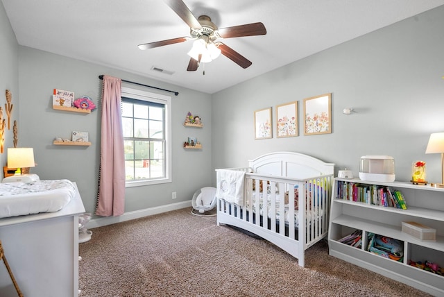 carpeted bedroom with ceiling fan and a nursery area