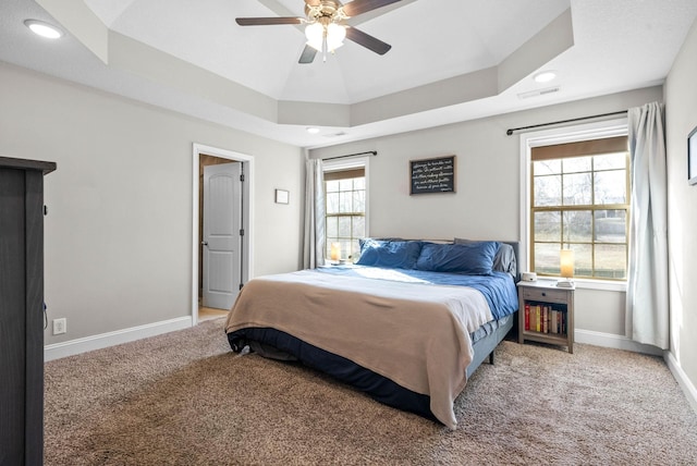 carpeted bedroom featuring a tray ceiling and ceiling fan