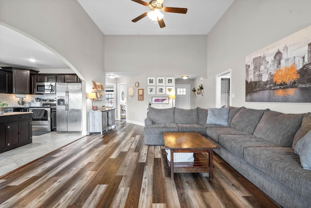 living room with hardwood / wood-style flooring, a towering ceiling, and ceiling fan