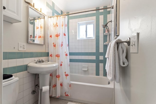 full bathroom featuring toilet, sink, tile walls, and shower / bath combo with shower curtain