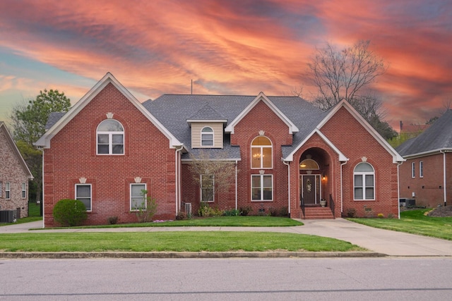 view of front of house featuring central AC unit and a yard