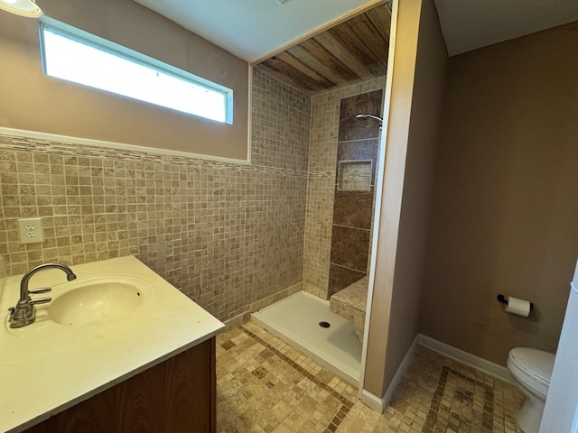 bathroom featuring a tile shower, vanity, and toilet