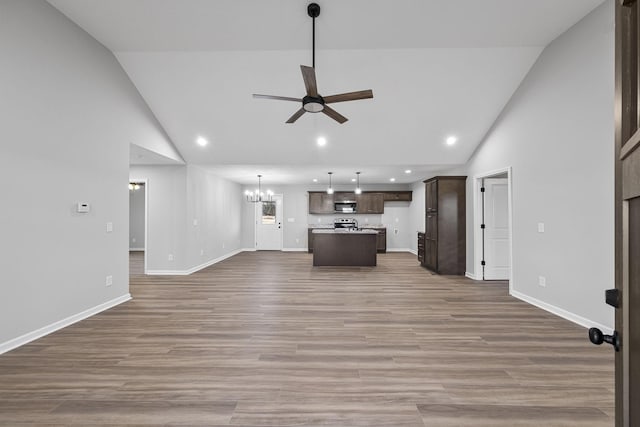 unfurnished living room featuring hardwood / wood-style floors, ceiling fan with notable chandelier, and high vaulted ceiling