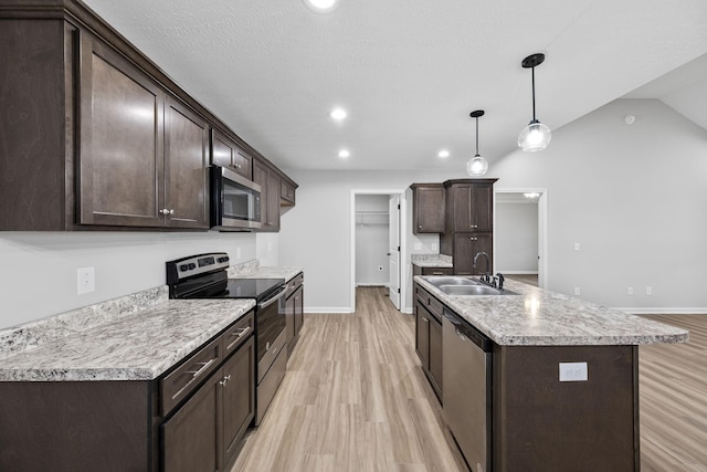 kitchen featuring appliances with stainless steel finishes, decorative light fixtures, sink, dark brown cabinetry, and a center island with sink