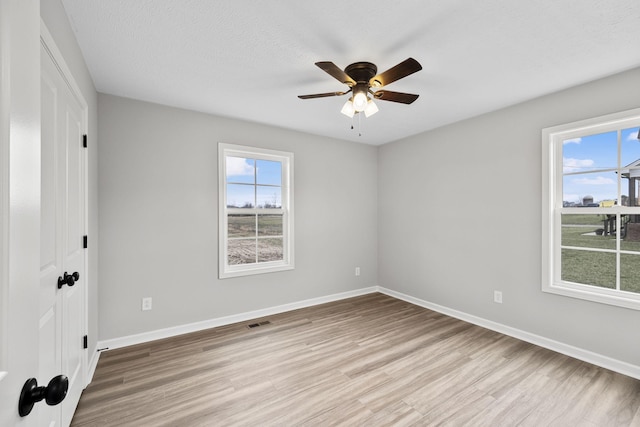 unfurnished bedroom with multiple windows, ceiling fan, a textured ceiling, and light hardwood / wood-style floors