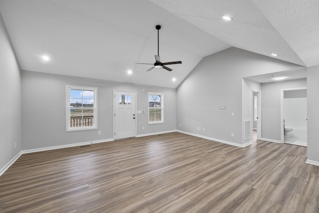 unfurnished living room with ceiling fan, lofted ceiling, a healthy amount of sunlight, and hardwood / wood-style floors