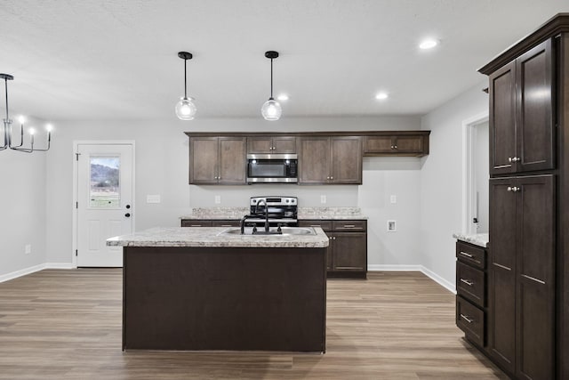 kitchen with a kitchen island, appliances with stainless steel finishes, light hardwood / wood-style floors, and decorative light fixtures