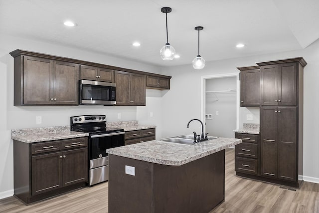 kitchen with sink, hanging light fixtures, light hardwood / wood-style flooring, an island with sink, and stainless steel appliances