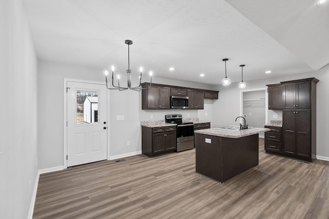 kitchen featuring appliances with stainless steel finishes, sink, a center island with sink, and decorative light fixtures