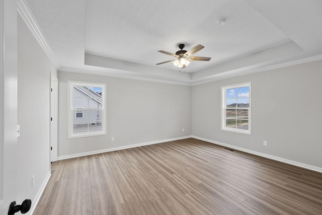 unfurnished room with a raised ceiling, wood-type flooring, ceiling fan, and a textured ceiling