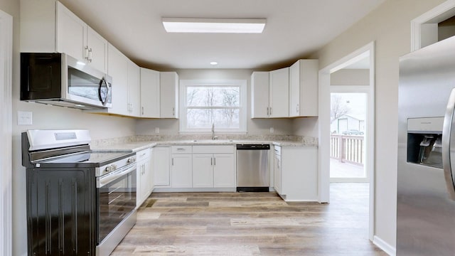 kitchen featuring light wood-type flooring, appliances with stainless steel finishes, sink, and white cabinets