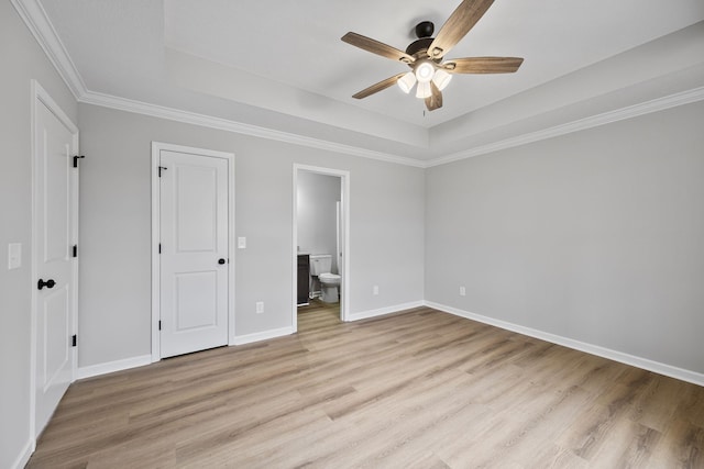 unfurnished bedroom featuring ceiling fan, ensuite bath, a raised ceiling, and light hardwood / wood-style floors