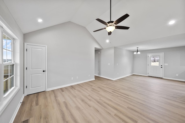 unfurnished living room with ceiling fan with notable chandelier, vaulted ceiling, and light wood-type flooring