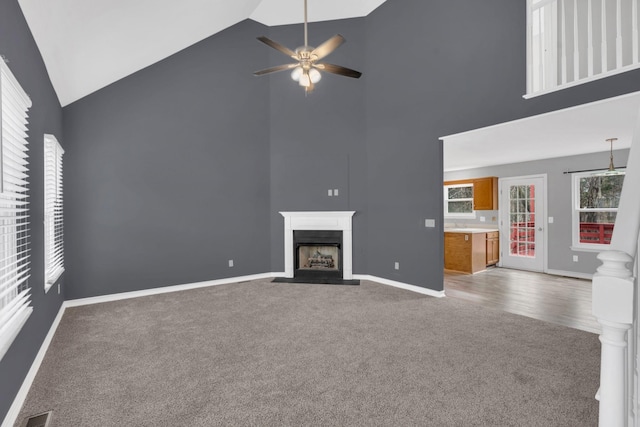 unfurnished living room featuring high vaulted ceiling, ceiling fan, and carpet flooring