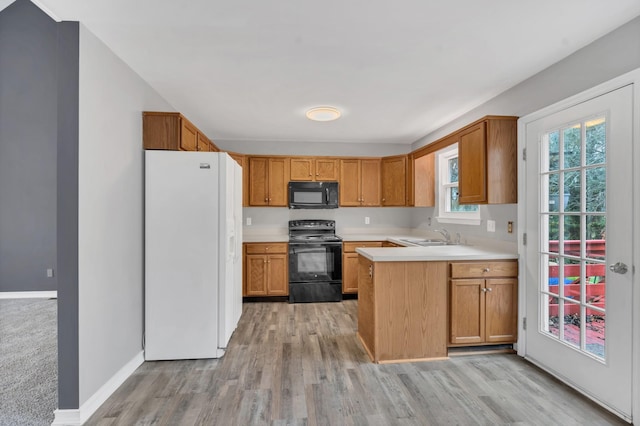 kitchen featuring sink, kitchen peninsula, light hardwood / wood-style floors, and black appliances