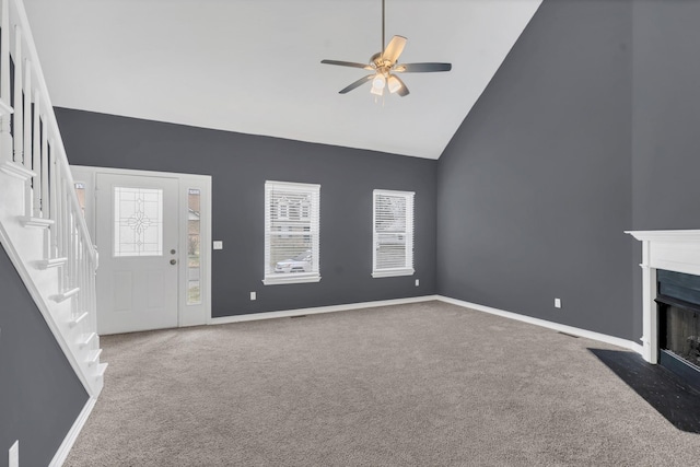 unfurnished living room with a wealth of natural light, carpet floors, high vaulted ceiling, and ceiling fan