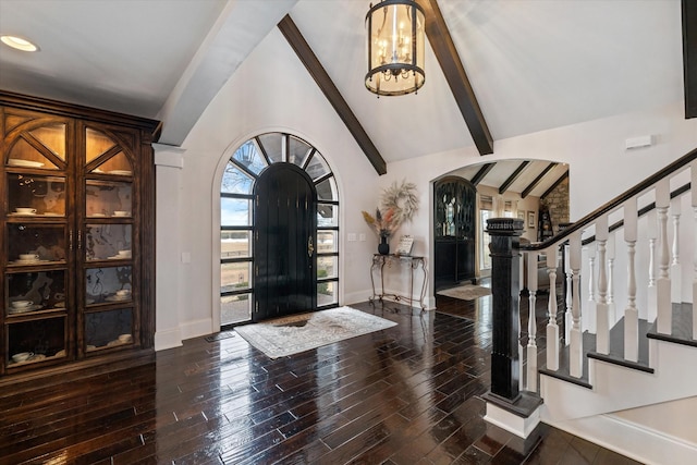 foyer entrance with arched walkways, baseboards, stairway, dark wood-style floors, and beamed ceiling