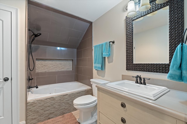 bathroom featuring tiled shower / bath combo, vaulted ceiling, vanity, and toilet