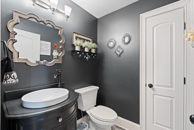 half bathroom with toilet, vanity, and baseboards