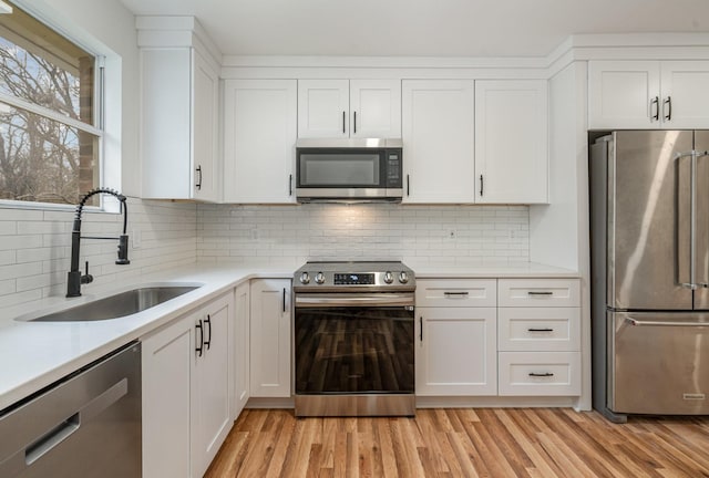 kitchen featuring white cabinetry, appliances with stainless steel finishes, light countertops, and a sink