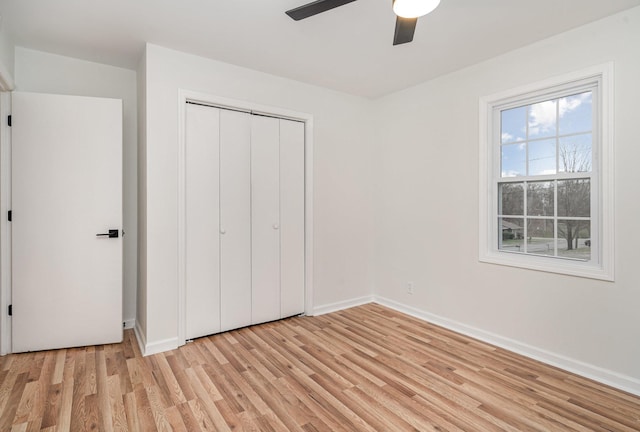 unfurnished bedroom with ceiling fan, a closet, light wood-type flooring, and baseboards