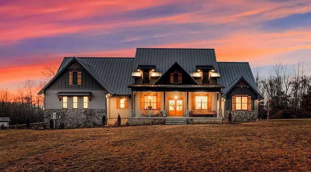 rear view of property with a porch, a standing seam roof, metal roof, and a chimney